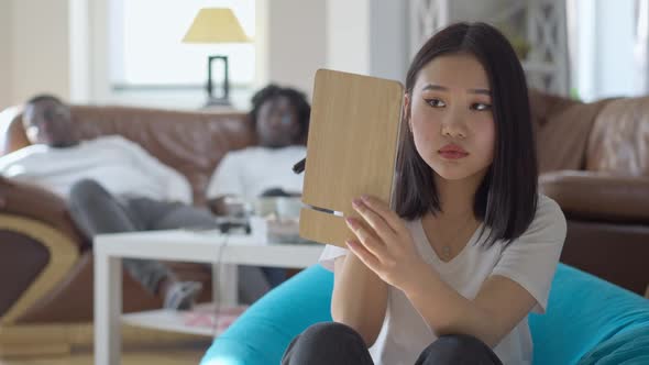 Portrait of Young Asian Beautiful Woman Applying Face Powder As African American Men Waiting Sitting