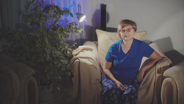 Portrait of Happy Elderly Woman Sitting in the Armchair at Home