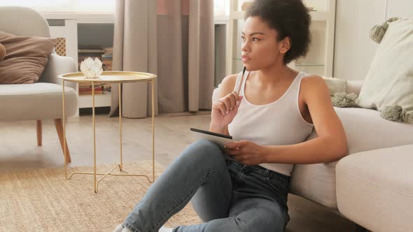 African american inspired woman pensively thinks and making notes in paper diary notebook.