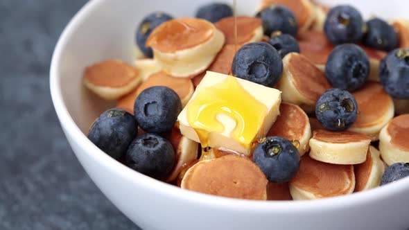 Pancake Cereal with Syrup, Butter and Berries in a White Bowl, Tiny Pancakes