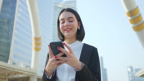 Asian office young woman feeling happy after she looking at smartphone having a chat in outdoor city