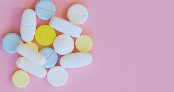 Top View Rotation  Pills and Capsules on a Pink Background