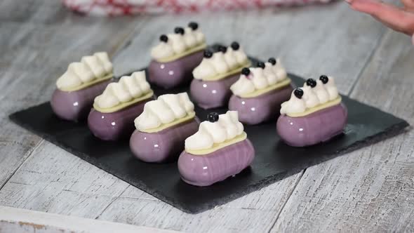 Confectioner decorates mousse cake with a blueberries Production of glazed desserts