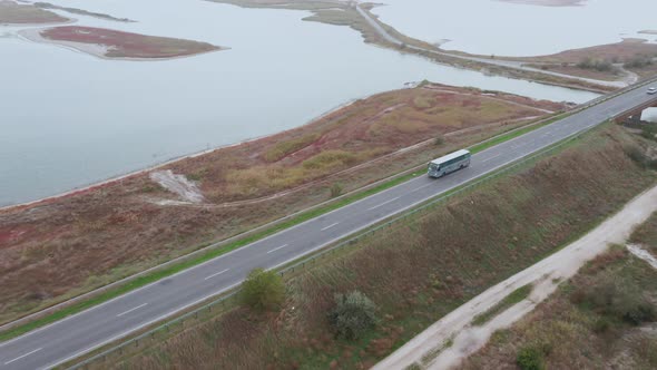 Aerial View of a Bus Driving Along a Highway Beside the Shoreline of a Lake.