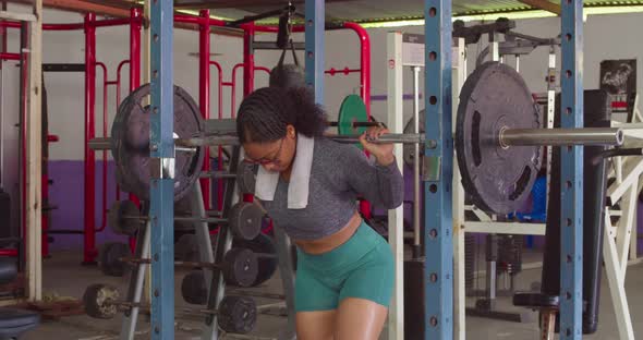 Young female body builder preparing to squat using weights at the gym