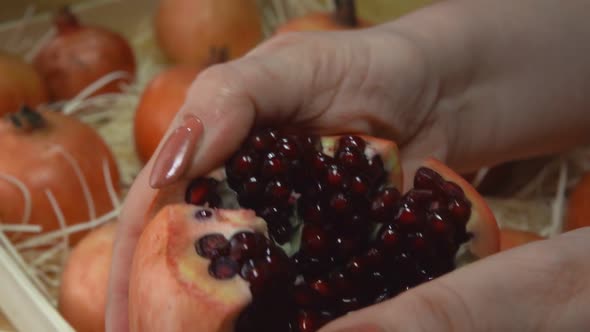 Female Hands are Breaking a Juicy Pomegranate Into the Six Pieces