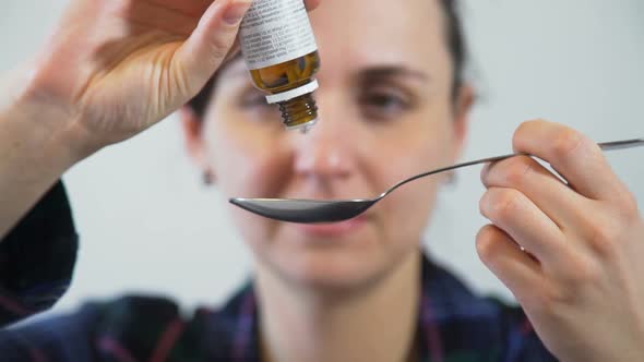 Woman Dripping Medicine From Vial Into the Spoon