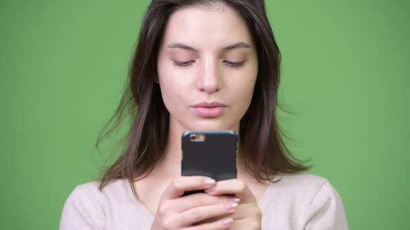 Young Beautiful Woman Using Phone Against Green Background