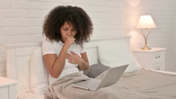 Young African Woman with Laptop Coughing in Bed