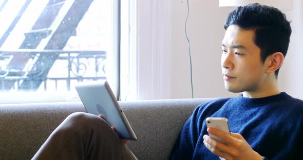 Man using digital tablet and mobile phone in living room 4k