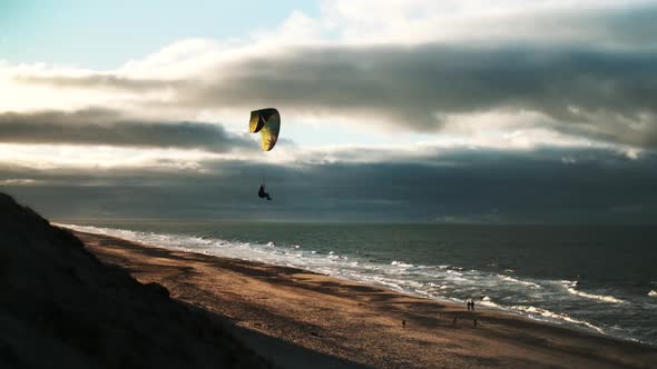 Man Paragliding Over Beach