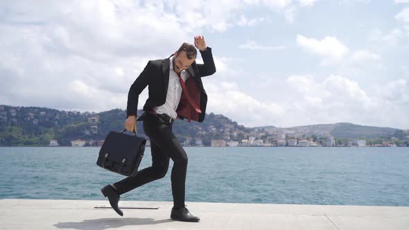 Businessman dancing happily by the sea.