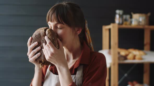 Happy Woman Smelling Loaf of Freshly Baked Rye Bread