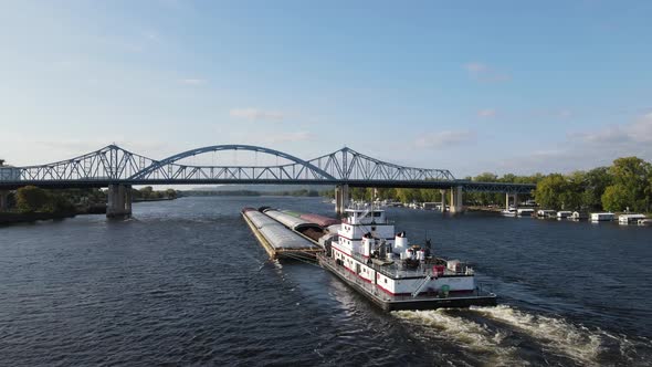 Tub boat pushing full barges under the big blue bridges and down the Mississippi River.