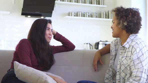 Two Girlfriends Gossiping While Sitting on the Couch