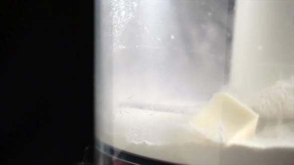 Butter cubes falling into a mixer containing a bit of flour. Truck movement, macro closeup shot.