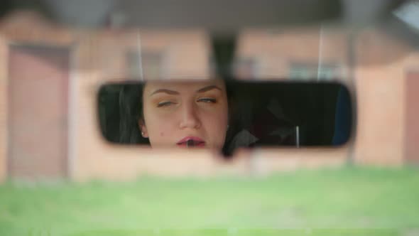 Woman Paints Her Lips in the Car Looking in the Rearview Mirror