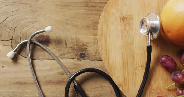 Video of close up of stethoscope with fruit on wooden table