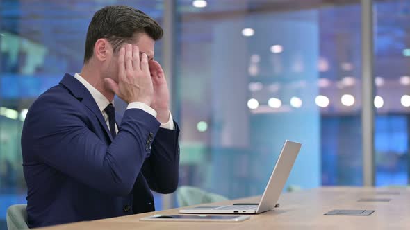 Businessman Having Headache While Working on Laptop