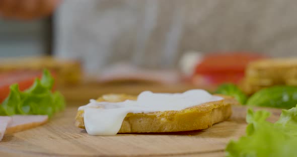 Female Chef in the Kitchen of the House Collects a Sandwich