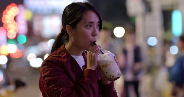 Woman enjoy iced bubble tea in city at night