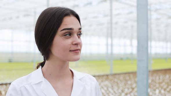 Man and Woman in Laboratory Robes Talk To Each Other Standing in the Greenhouse