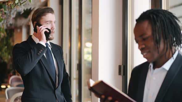 Serious Smartly Dressed Man Talking By Phone and Working at Cafe