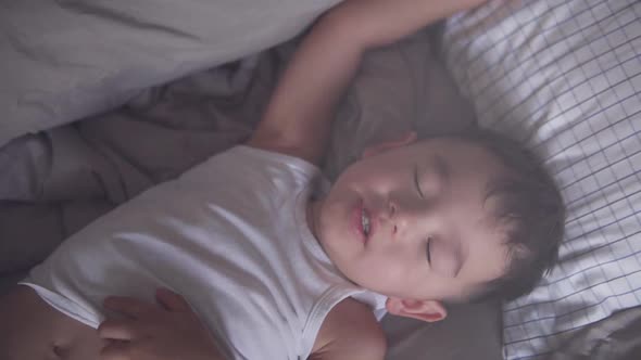 High angle shot of a little two years old Asian toddler dreaming and moving while sleeping maybe hav