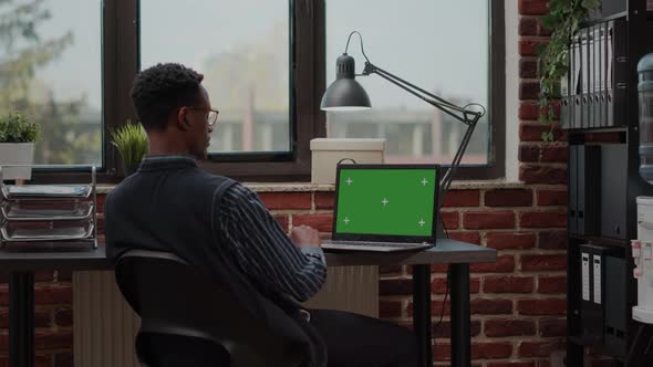 Male Secretary Analyzing Green Screen on Laptop in Startup Office