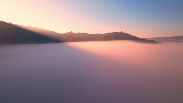 4K aerial view over a misty mountainous area. The great golden sun in the morning