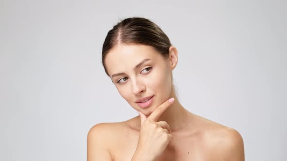 Beautiful Young Woman with Clean Fresh Skin Standing Over Light Grey Background