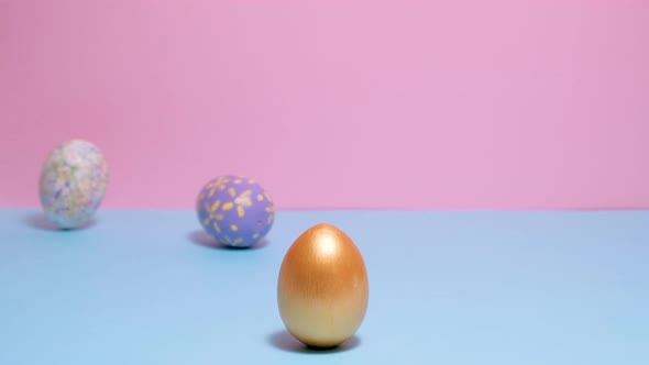 Colorful Painted Easter Eggs Roll and Knock Each Other on a Blue and Pink Background