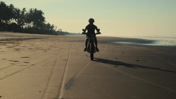 Silhouette of a Biker on the Tropical Coastline at Dusk