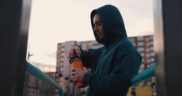 Man on the Sports Ground Closes Thermos and Finish His Training