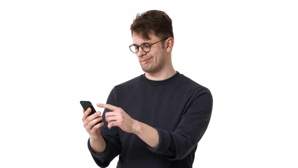 Portrait of Happy Man 20s Wearing Black Sweatshirt and Glasses Browsing Internet on Smartphone