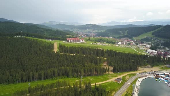 Aerial view of a big lake surrounded with high green mountains covered in spruce forest