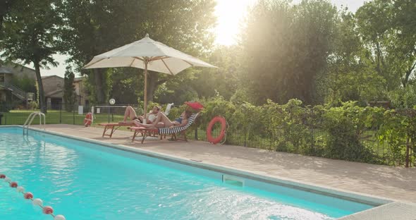 Beautiful Romantic Couple Relaxing and Sunbathing Near Swimming Pool at Luxury Rural Villa House