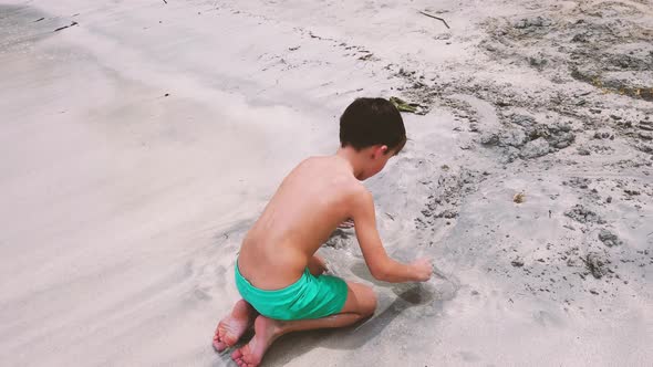 Slow motion shot of boy digging in sand, Mauritius