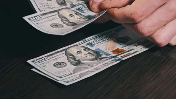 Counting New Hundred Dollar Banknotes on a Black Wooden Table