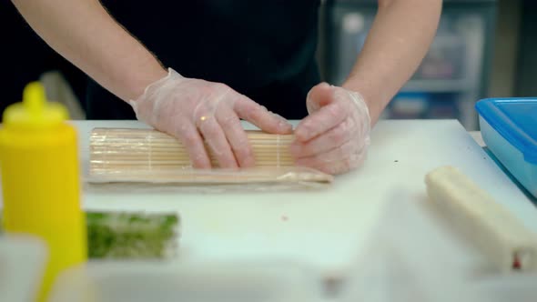 Cook Prepares a Japanese Roll with Rice and Bacon