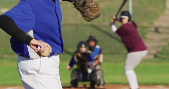 Diverse group of female baseball players in action on the field, pitched ball caught by catcher