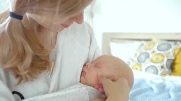 mother stroking a sleeping baby in her arms