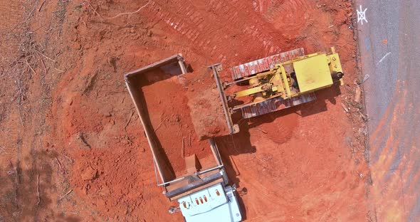 An Excavator is Loading Earth Into a Dump Truck Which is Heavy Construction Equipment