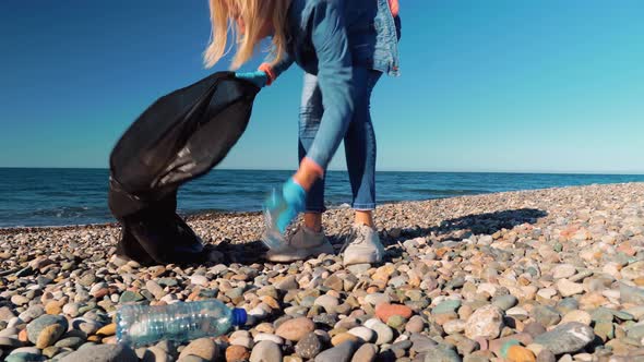 a woman collecting cleaning plastic bottles on the beach,