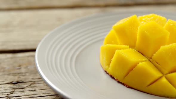 Chopped mangoes in plate on wooden table