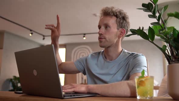 Attractive guy freelancer works at the table on a laptop