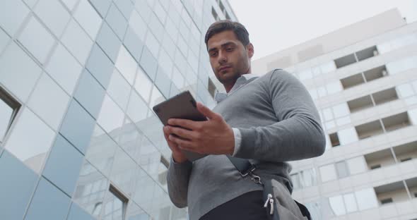 Bottom View of Confident Indian Businessman Working on Tablet Outdoors