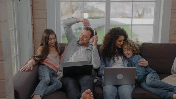 Boy and Girl Run to Their Parents Working Sitting on a Couch to Hug Them