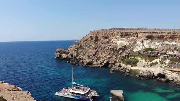 Natures majestic view of the Anchor Bay from Popeye village in Malta; stranded boat with people enjo