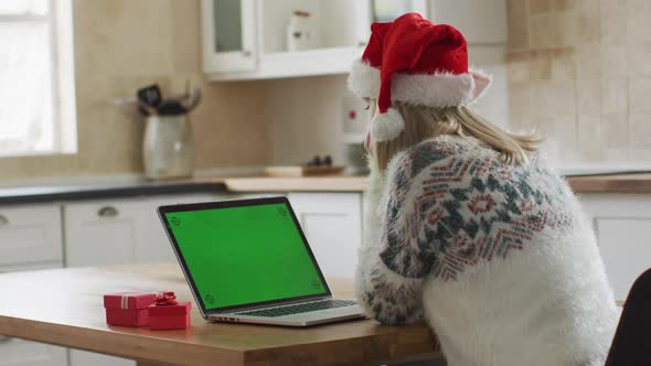 Woman wearing Santa hat having a video chat on her laptop at home